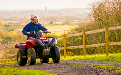 A quad bike trekking up a hill with Warwick town in the background