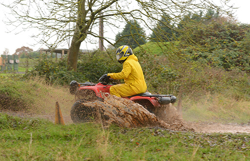 Someone on a quad bike going through muddy water