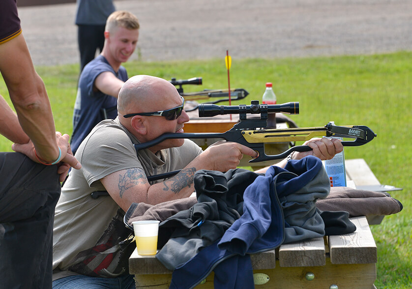A man aiming down the sights of a crossbow