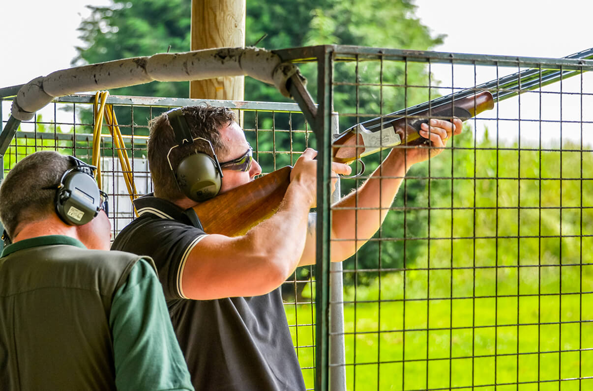 Someone being taught how to shoot, stood in a cage