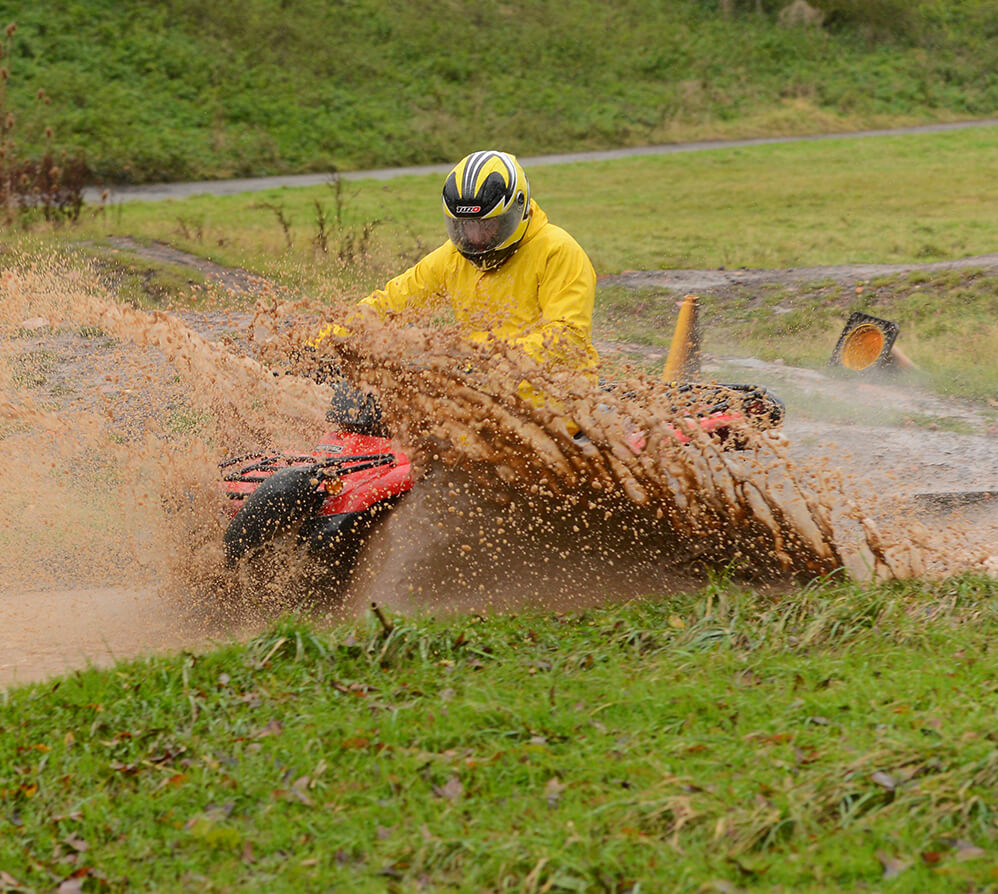 Someone driving a quad bike through a muddy puddle