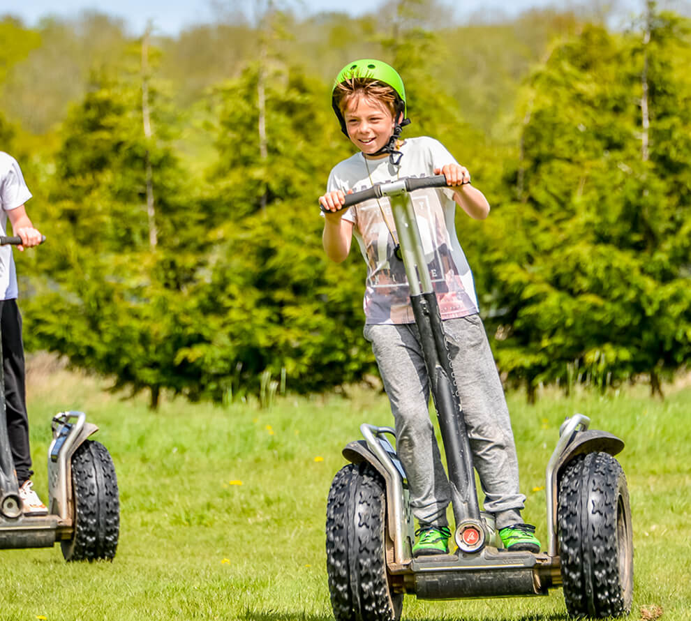 A young boy driving a segway with a friend
