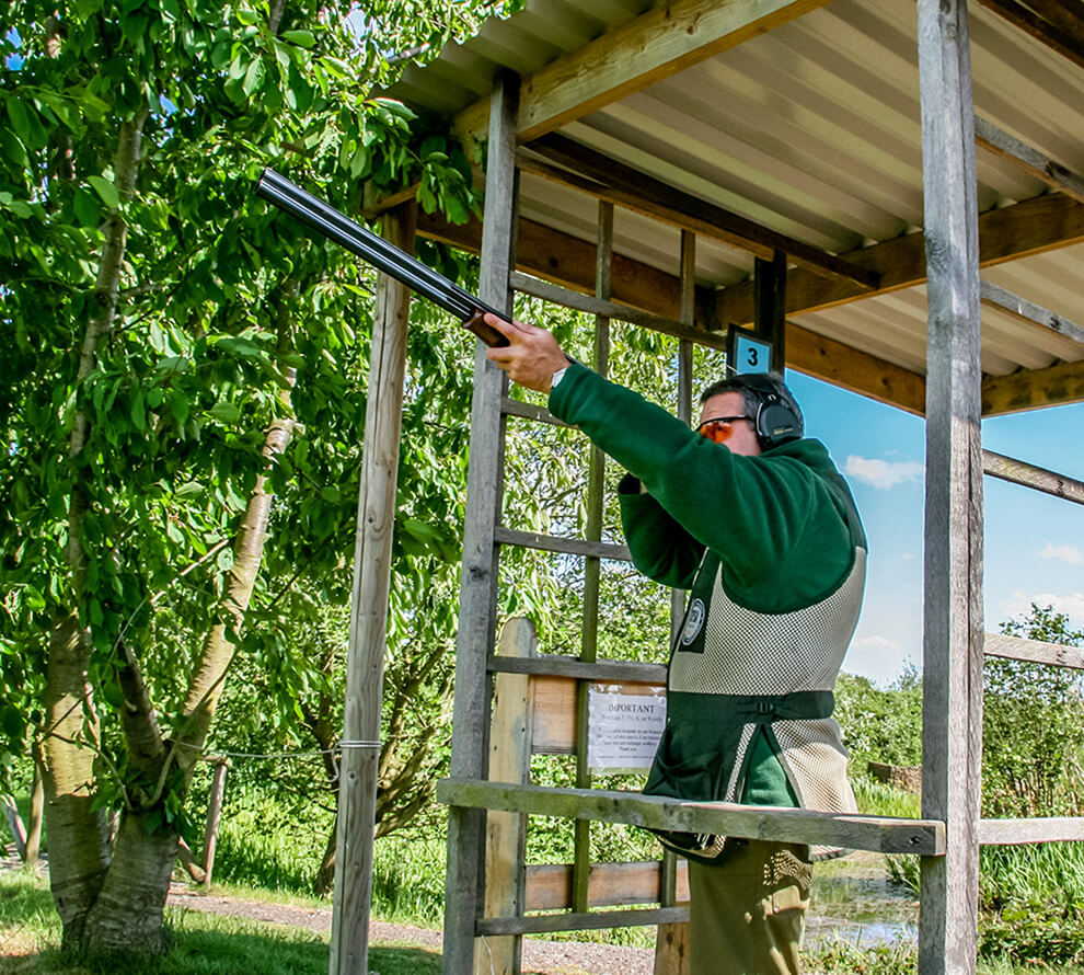 A man with full protective gear aiming down range with his shotgun