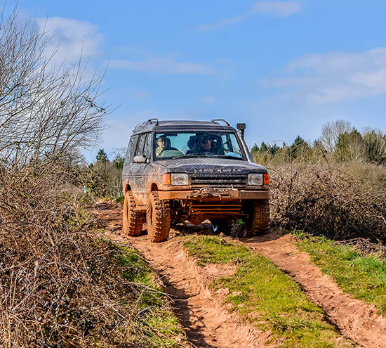 A Land Rover driving across a muddy field