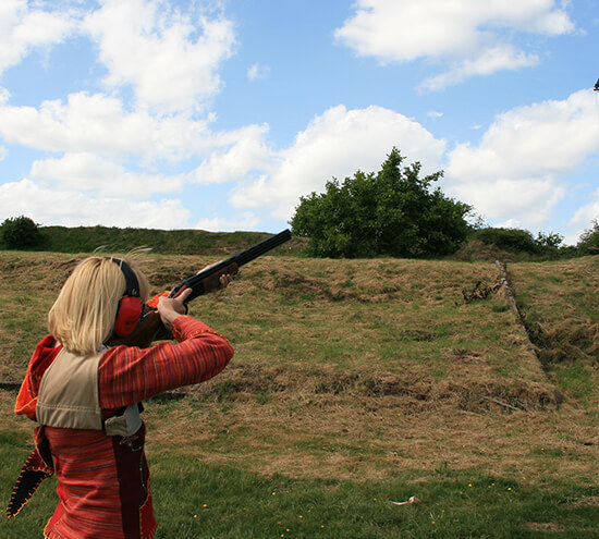 A woman aiming down range with her shotgun