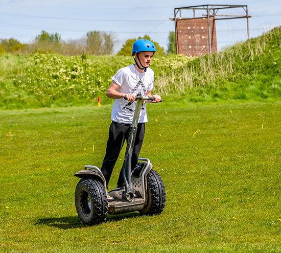 A young boy driving a segway and leaning forward