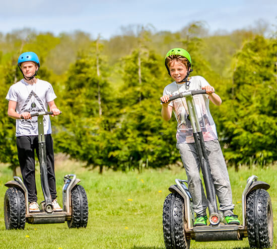 Two boys driving segways in a field