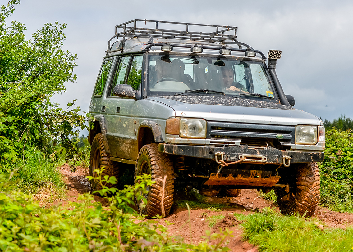 A Land Rover car driving over a muddy field
