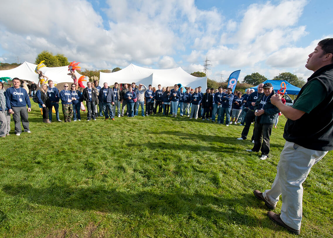 A group of workers stood in a circle listening to someone talk