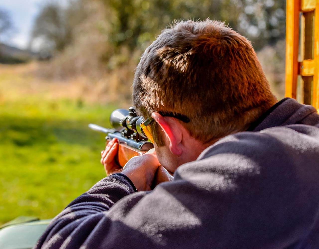 A man aiming down a range with a rifle