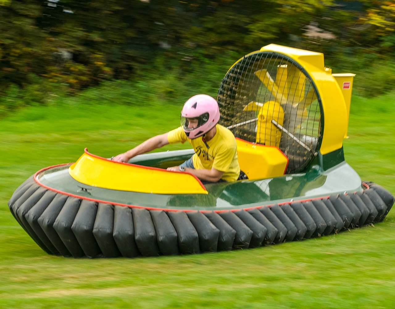 A man driving a hovercraft quickly across a field