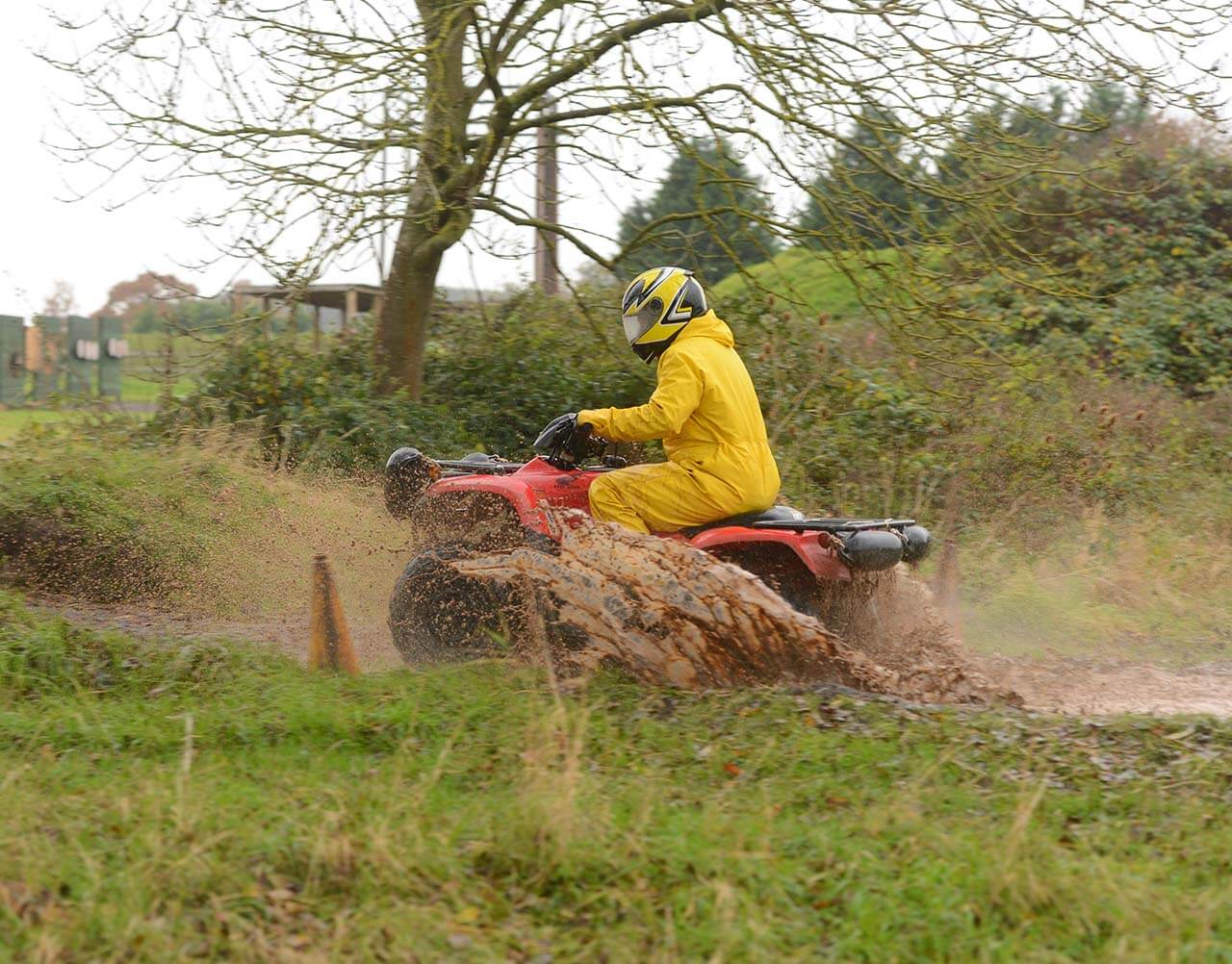 A quad bike being driven through a muddy puddle