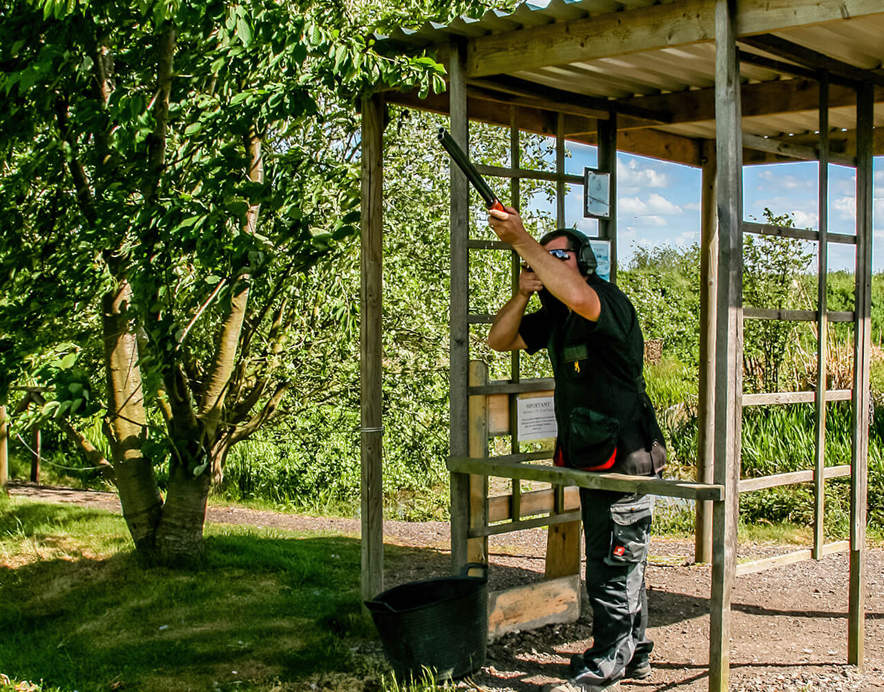 A man aiming down range with a shotgun