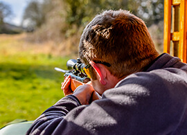 A man aiming down range with a rifle