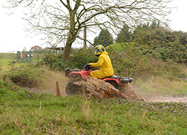 Someone on a quad bike driving through a muddy puddle