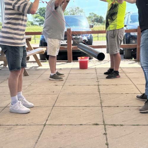 Team working together on the Level Crossing outdoor team building challenge at Adventure Sports in Warwick