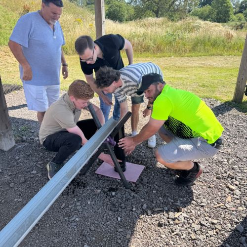 Corporate group working together to solve the Plumber&rsquo;s Nightmare team building challenge at Adventure Sports Warwick