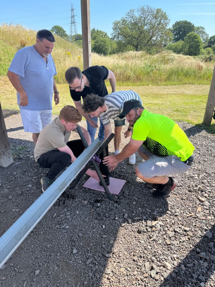 Corporate group working together to solve the Plumber&rsquo;s Nightmare team building challenge at Adventure Sports Warwick